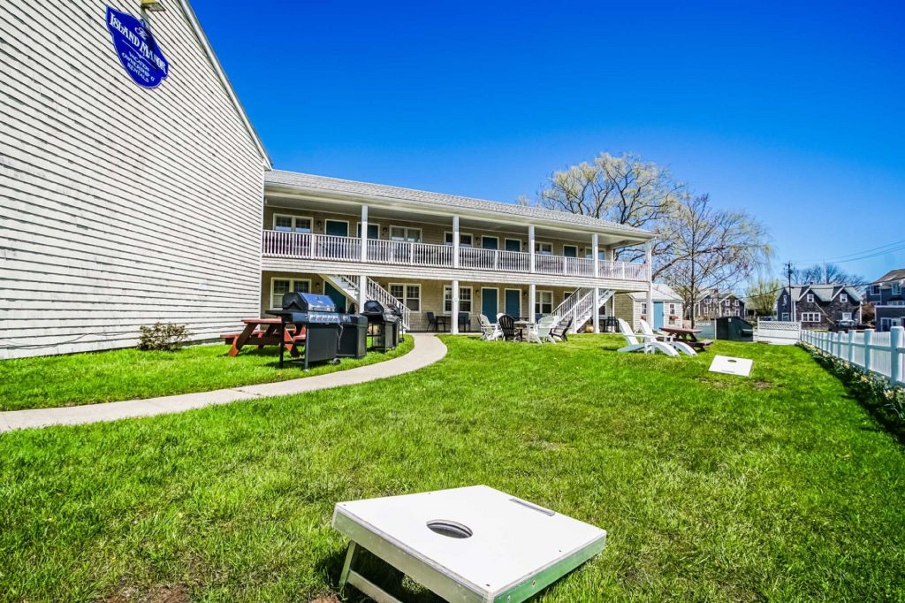 A two-story building with a covered patio area, outdoor seating, and a grill.