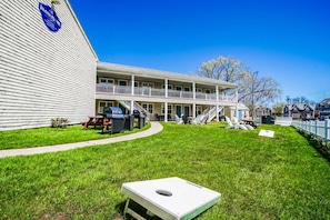 A two-story building with a covered patio area, outdoor seating, and a grill. - Island Manor Resort by VRHost (Block Island)