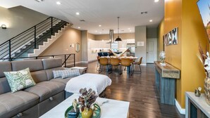 A modern living room with a sofa, coffee table, and a dining area with chairs and a table.