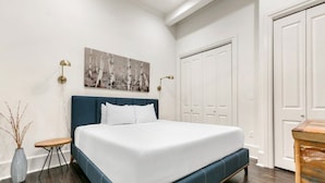 Une chambre à coucher avec un grand lit, une table de chevet, une lampe, un tableau au mur et une armoire.