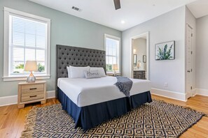 Une chambre avec un grand lit, deux tables de chevet, un tapis à motifs et une fenêtre avec des stores.