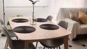 Uma área de refeições moderna com uma mesa de madeira, jogos americanos trançados pretos e cadeiras pretas.