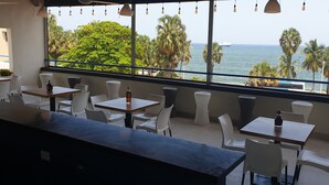 Un restaurant doté d’une terrasse, de grandes fenêtres et offrant une vue sur la mer.