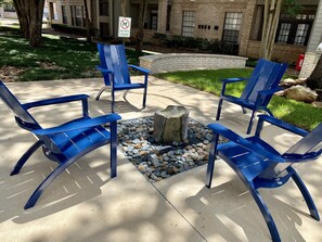 Outdoor seating with a fire pit, a 'No Pets' sign, and a building in the background. - Central Houston- Urban Living (Houston)