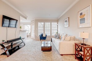 A living room with a flat-screen TV, a sofa, a coffee table, and a TV stand. - Central Houston- Urban Living (Houston)
