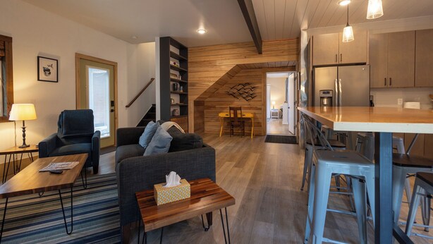 A modern kitchen with wooden cabinets and stainless steel appliances, a dining area with a table and chairs, and a living room with a sofa and a coffee table. - Great Family Getaway on the East side of Traverse City (Traverse City)