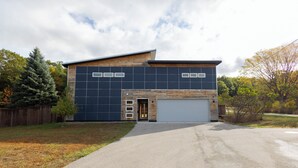 A modern two-story building with a garage, a paved driveway, and a wooden fence. - Great Family Getaway on the East side of Traverse City (Traverse City)