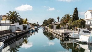 Un canal con barcos, palmeras y edificios a lo largo de las orillas.