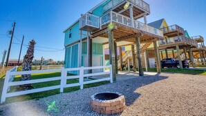 A two-story building with a balcony and a deck, surrounded by a white fence and a gravel path. - Modern A-Frame | 3BR/2BA | Pet-Friendly | Steps to Beach | Huge Deck (Freeport)
