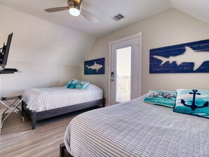 Un dormitorio con dos camas, un ventilador de techo y decoración temática náutica.