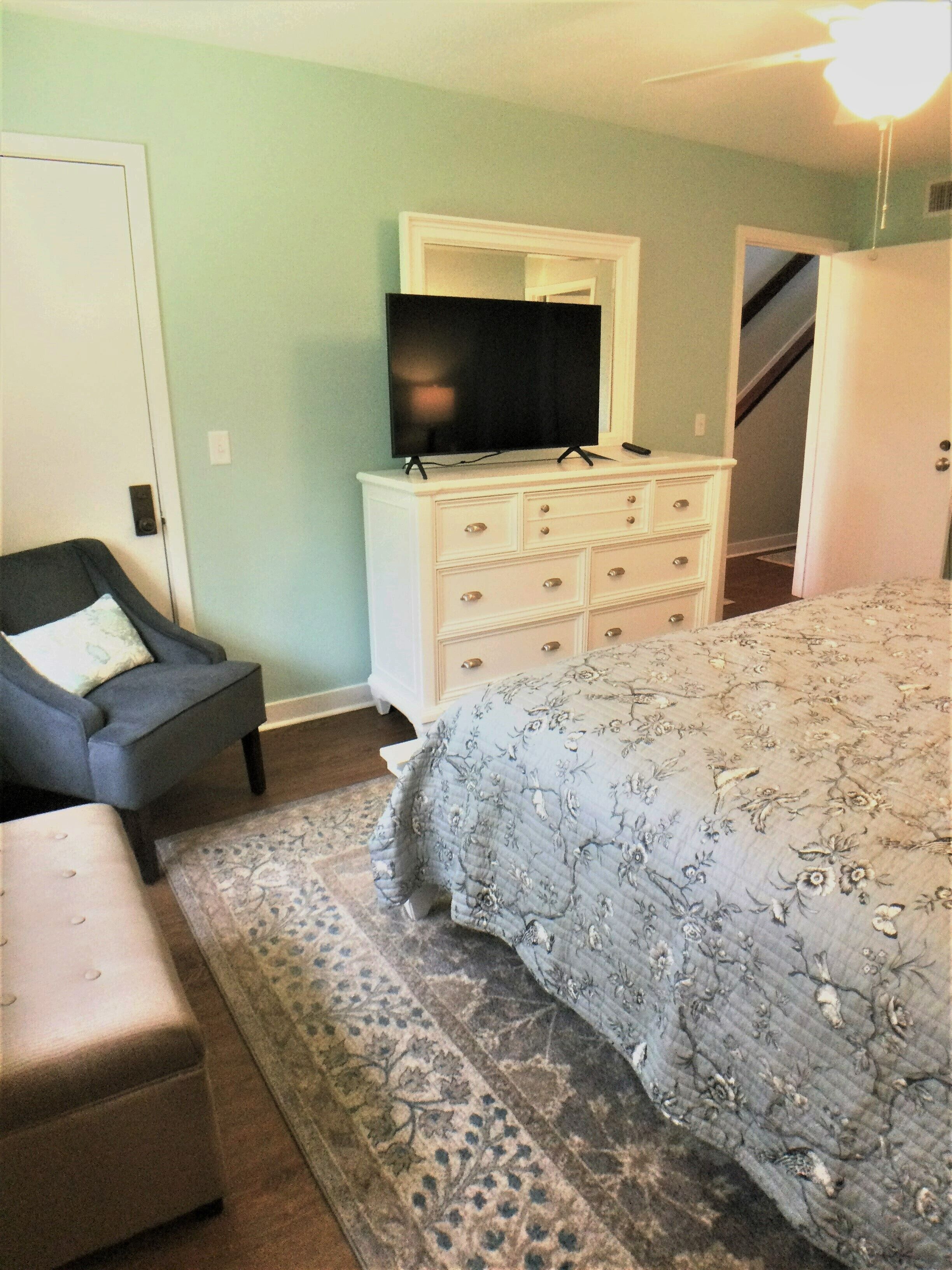A bedroom with a bed, a dresser, a chair, and a television.