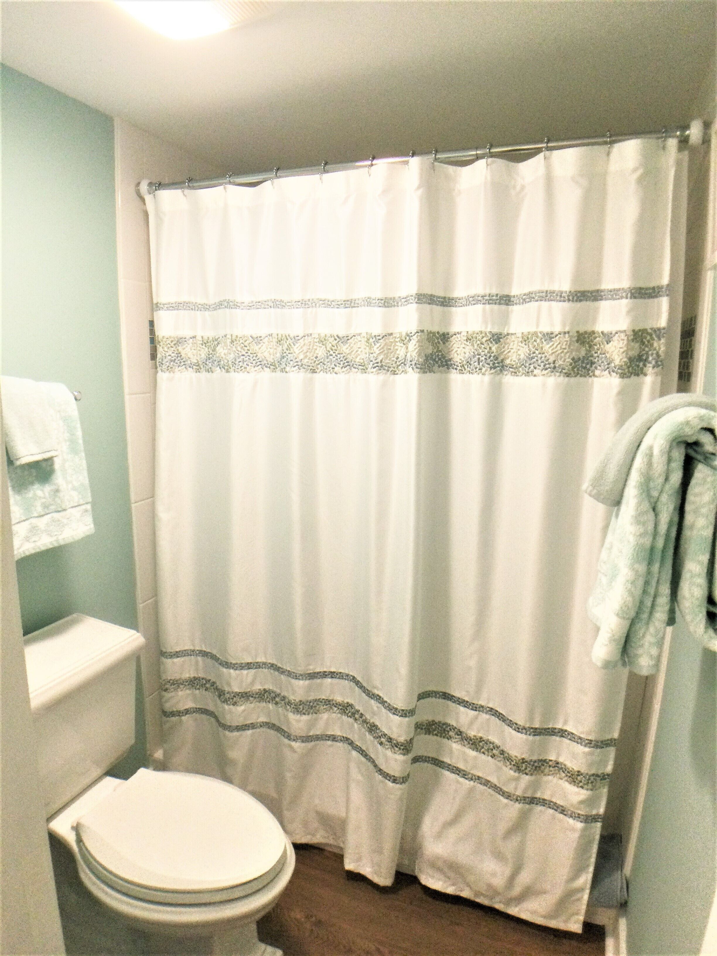 A bathroom with a toilet, a shower curtain, and a towel rack.