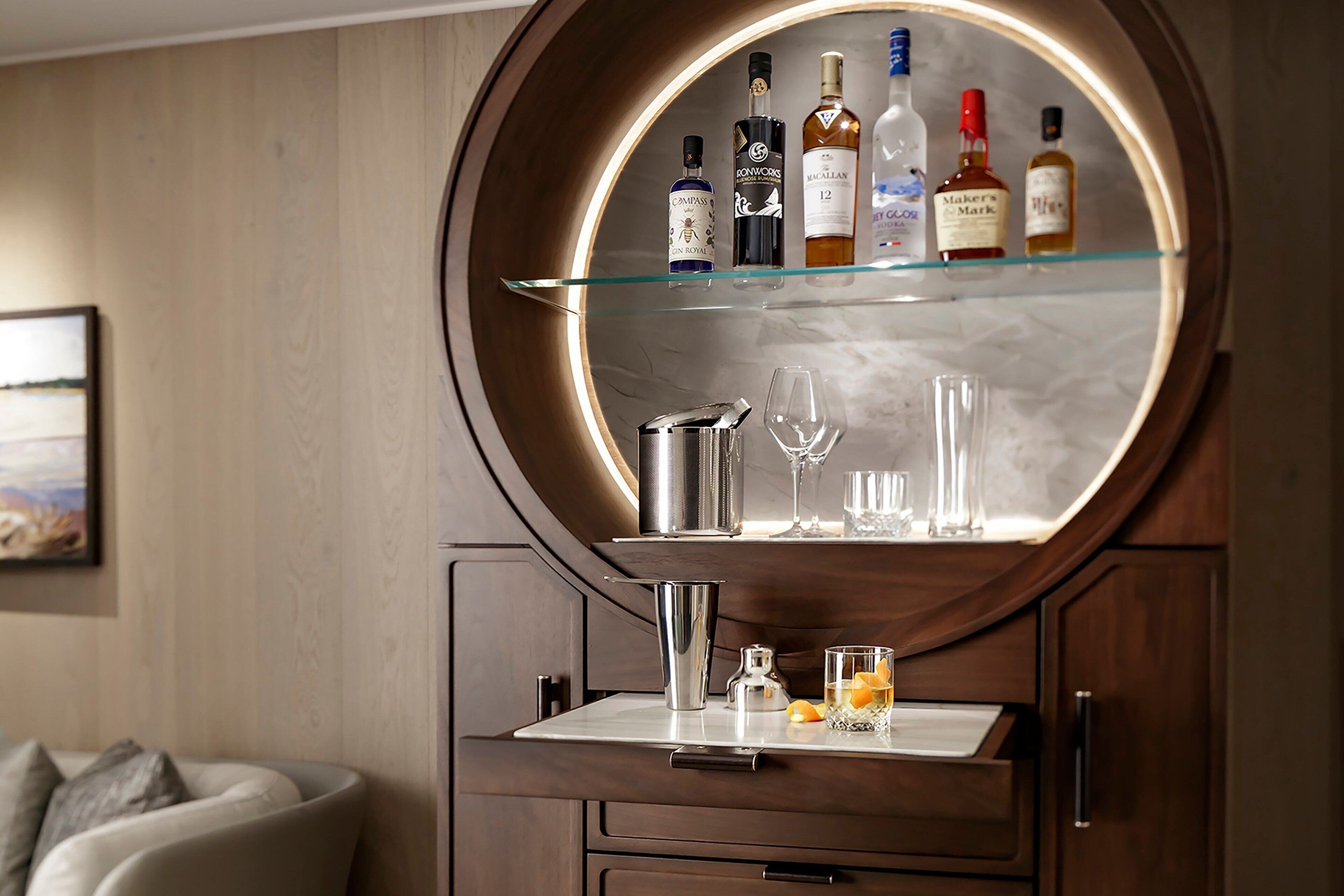 Un coin bar avec un grand miroir rond, une bouteille de whisky et un shaker à cocktails.