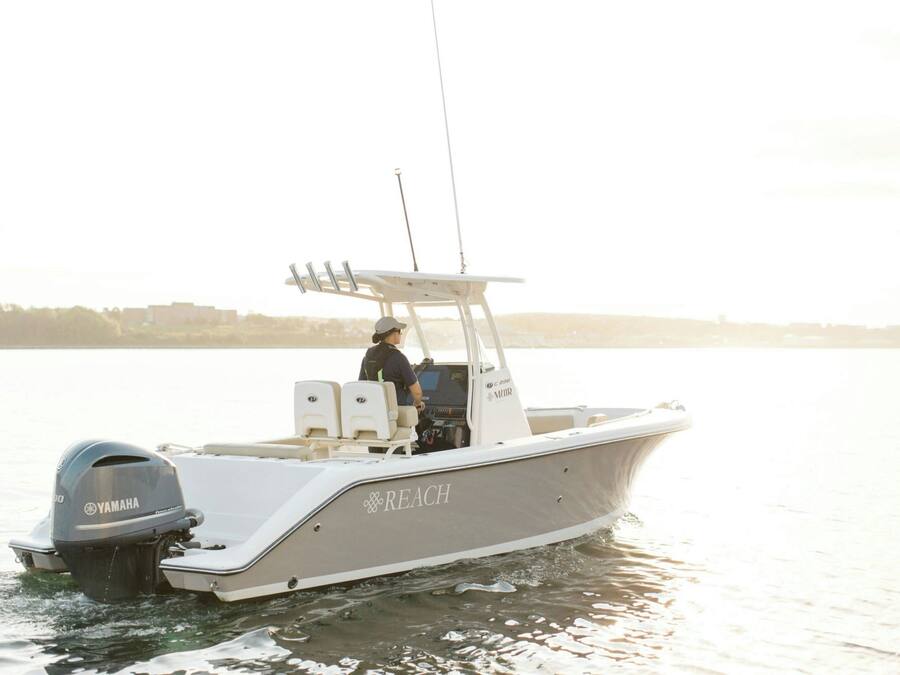 A motorboat with a Yamaha outboard motor, a white cabin, and the word "REACH" on the side.