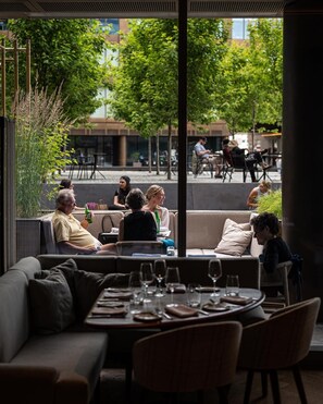 An outdoor seating area with tables and chairs, overlooking a street with people and buildings.
