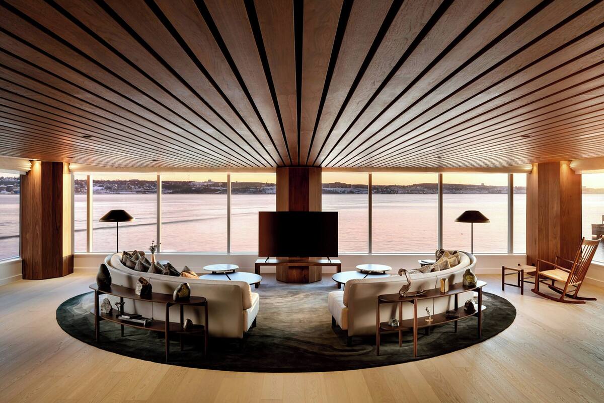 A spacious living room with a large TV, comfortable seating, and a view of a body of water.