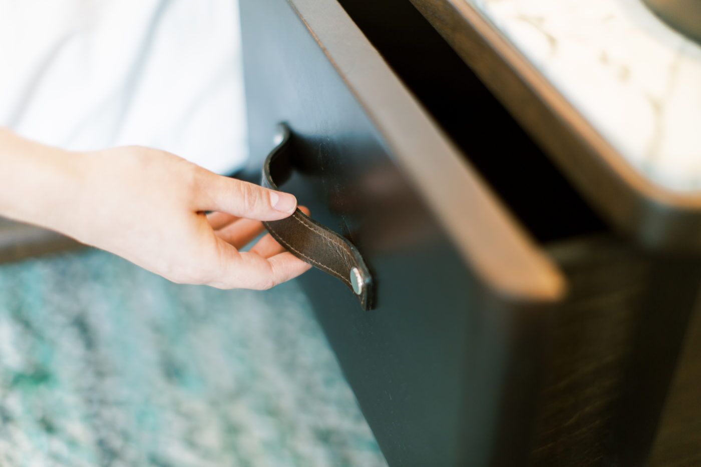 Une main tenant une clé près d’une poignée de porte.