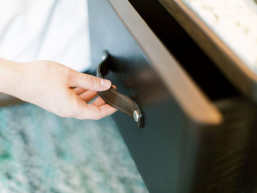 Une main tenant une clé près d’une poignée de porte.