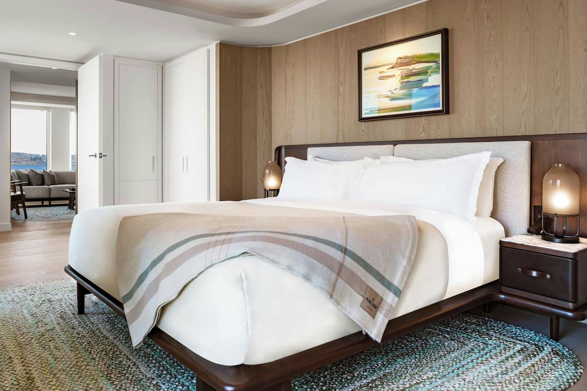 A modern hotel room with a large bed, wooden headboard, and a view of the outdoors.