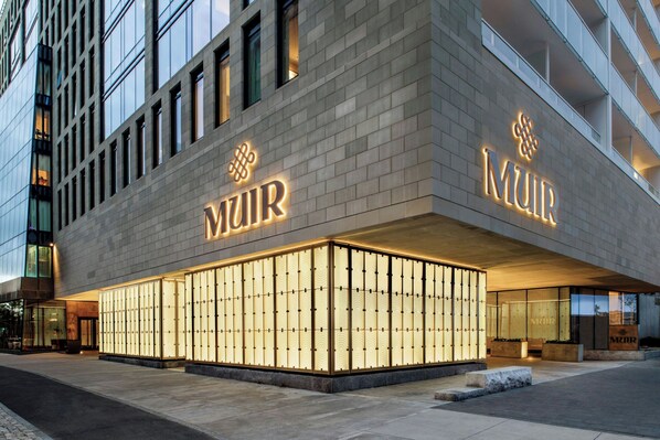 A modern building with the name 'MUIR' illuminated on the facade.