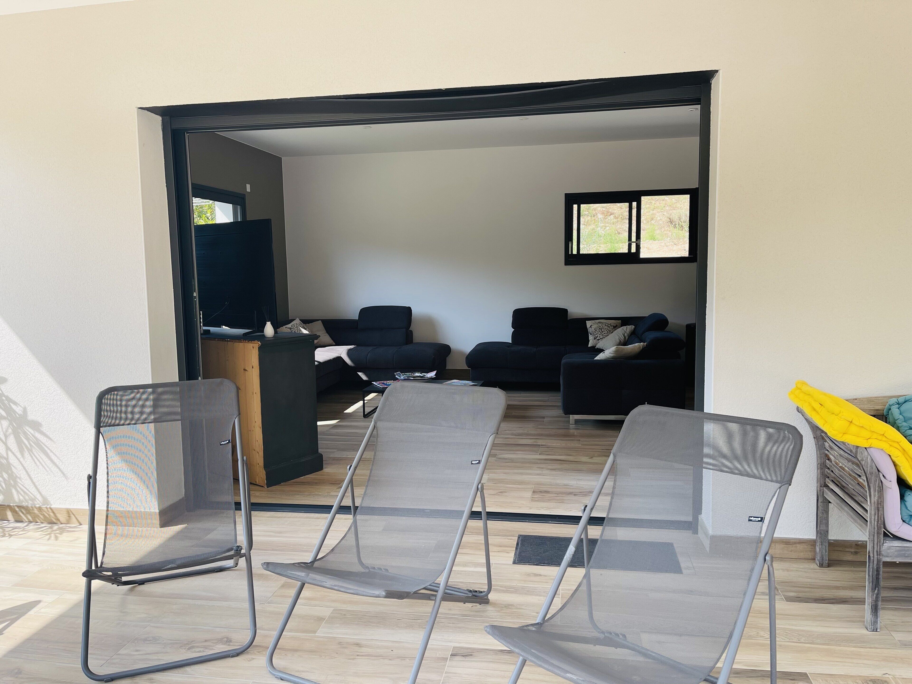A living room with a sofa set, a TV, and two folding chairs.