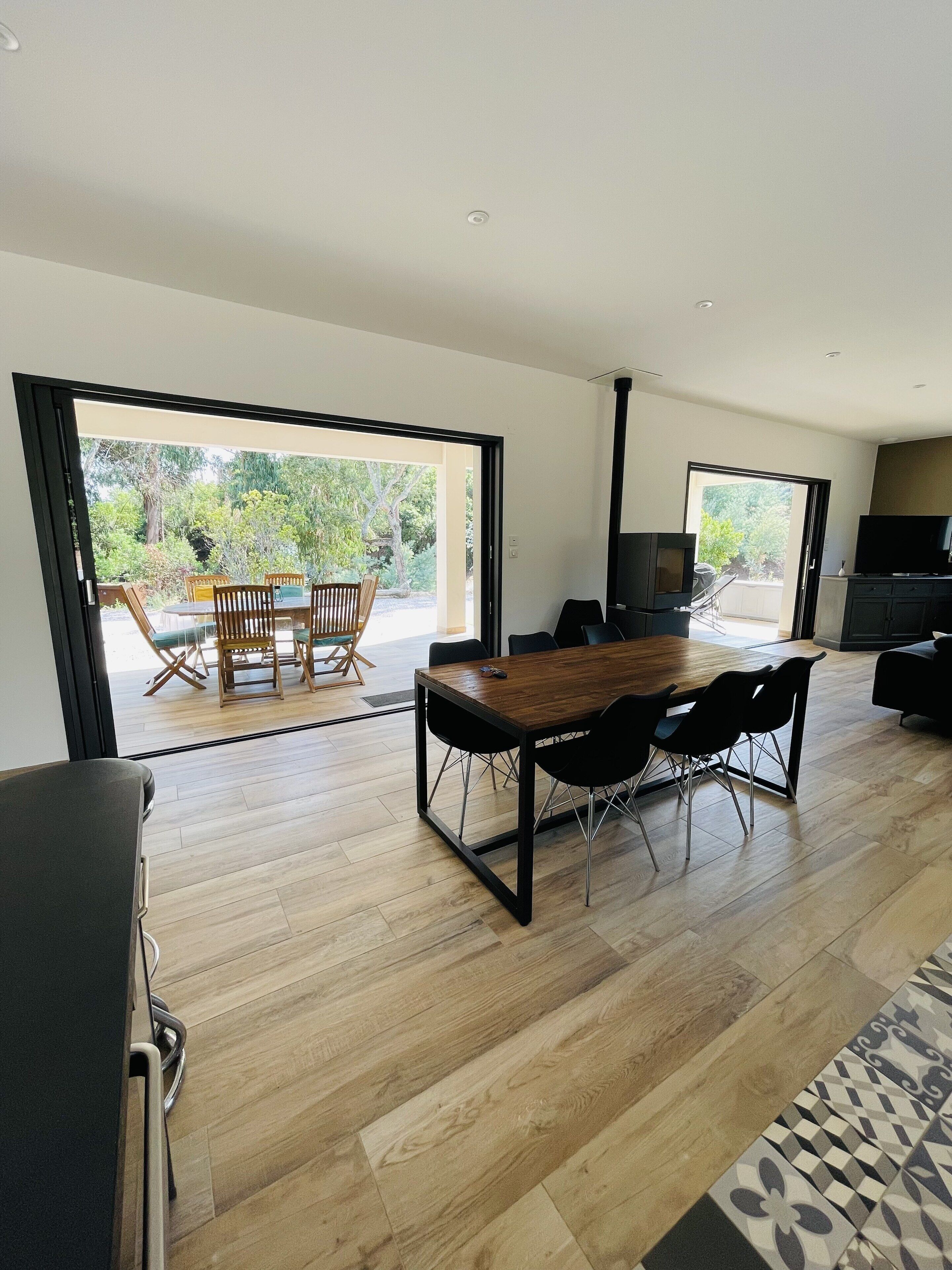 Een moderne woonkamer met een houten eettafel, zwarte stoelen en een televisie.