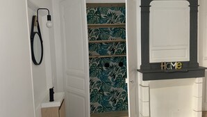 Ein Zimmer mit einer weißen Tür, einem Spiegel, einem Regal mit einem 'Home'-Schild und einer Wand mit tropischem Wandpapier.