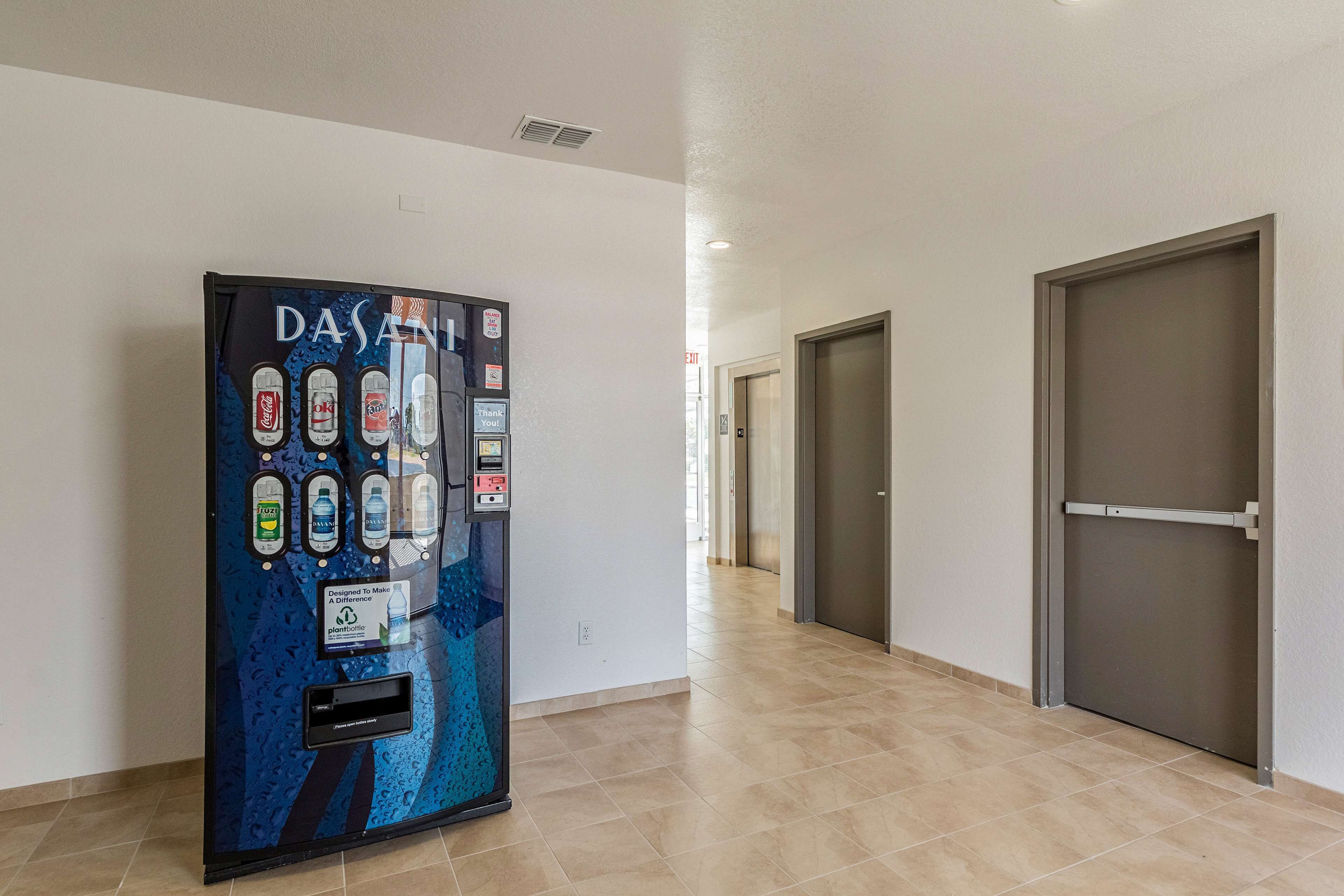 A hallway with a water dispenser, doors, and a tiled floor.