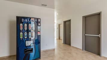 A hallway with a water dispenser, doors, and a tiled floor.