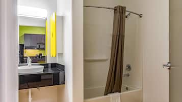 Un baño con bañera, cortina de ducha, lavabo y espejo.