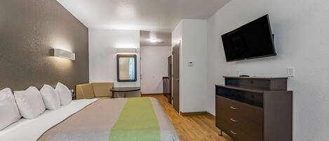 Una habitación de hotel con una cama, un tocador, un televisor y un pequeño escritorio con espejo.