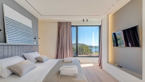 Een moderne hotelkamer met een groot bed, een flatscreen televisie en uitzicht op het groen.