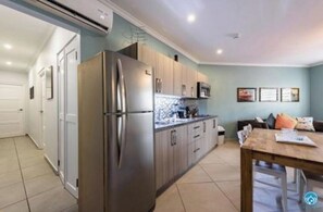 Una cocina moderna con electrodomésticos de acero inoxidable, armarios de colores claros y suelo de baldosas.