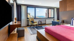 Ein Hotelzimmer mit einem großen Bett, einem Schreibtisch, einem Stuhl, einem kleinen Tisch und einem Fernseher.
