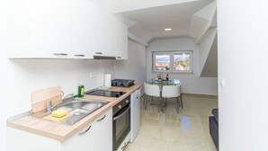 Une cuisine compacte équipée d’un évier, d’une cuisinière et d’un coin repas avec une table et des chaises en verre.