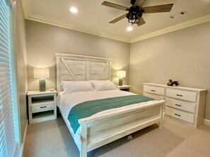 A neatly arranged bedroom with a bed, bedside tables, a dresser, and a ceiling fan.
