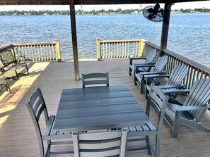 A wooden deck with a table and chairs, overlooking a body of water.