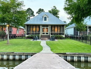 A house with a porch, a pathway leading to the water, and a small dock.