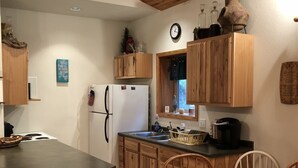 A kitchen with wooden cabinets, a refrigerator, a sink, and a dining table with chairs. - Rapid Creek Get Away (Hill City)