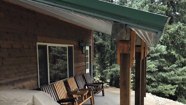 A wooden cabin with a covered patio area, outdoor seating, and a stone pathway. - Rapid Creek Get Away (Hill City)