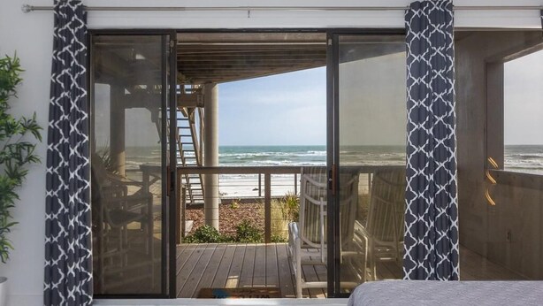 A room with a large sliding glass door leading to a balcony with a view of the ocean. - Beautiful Remodeled Oceanfront Condo ~ Best Location and Spectacular Views! (Saint Augustine)
