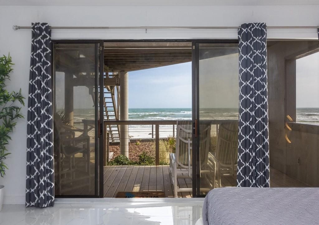 Een kamer met een grote schuifglazen deur die uitkomt op een balkon met uitzicht op de oceaan.