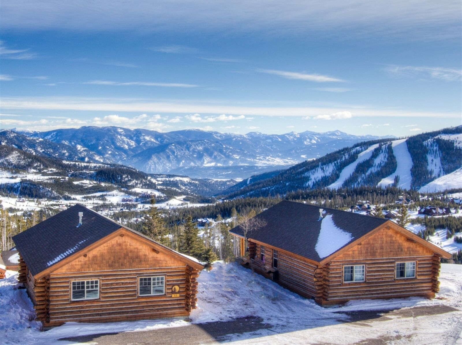 A log cabin with a view of snow-covered mountains.