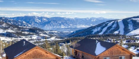 A log cabin with a view of snow-covered mountains.