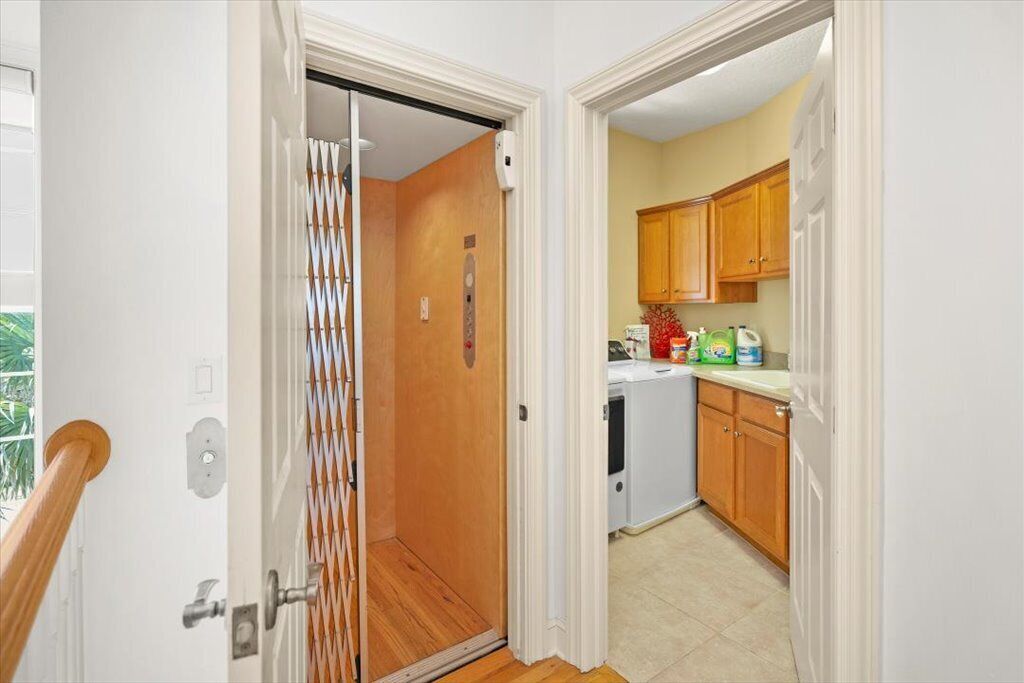 A narrow hallway leading to a kitchen with wooden cabinets and a washing machine.