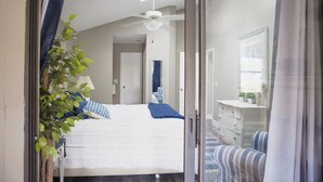 A bedroom with a bed, a ceiling fan, a dresser, and a mirror.