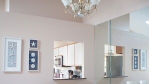 A dining area with a wooden table and white chairs, a chandelier, and framed artwork on the walls.