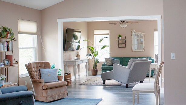 A spacious living room with a high ceiling, skylights, and a view into the dining area.