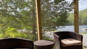 Terraza de madera con mobiliario de mimbre con vista a un lago.