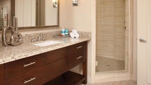 Une salle de bain avec un comptoir en marbre, un lavabo, un miroir et un espace douche.